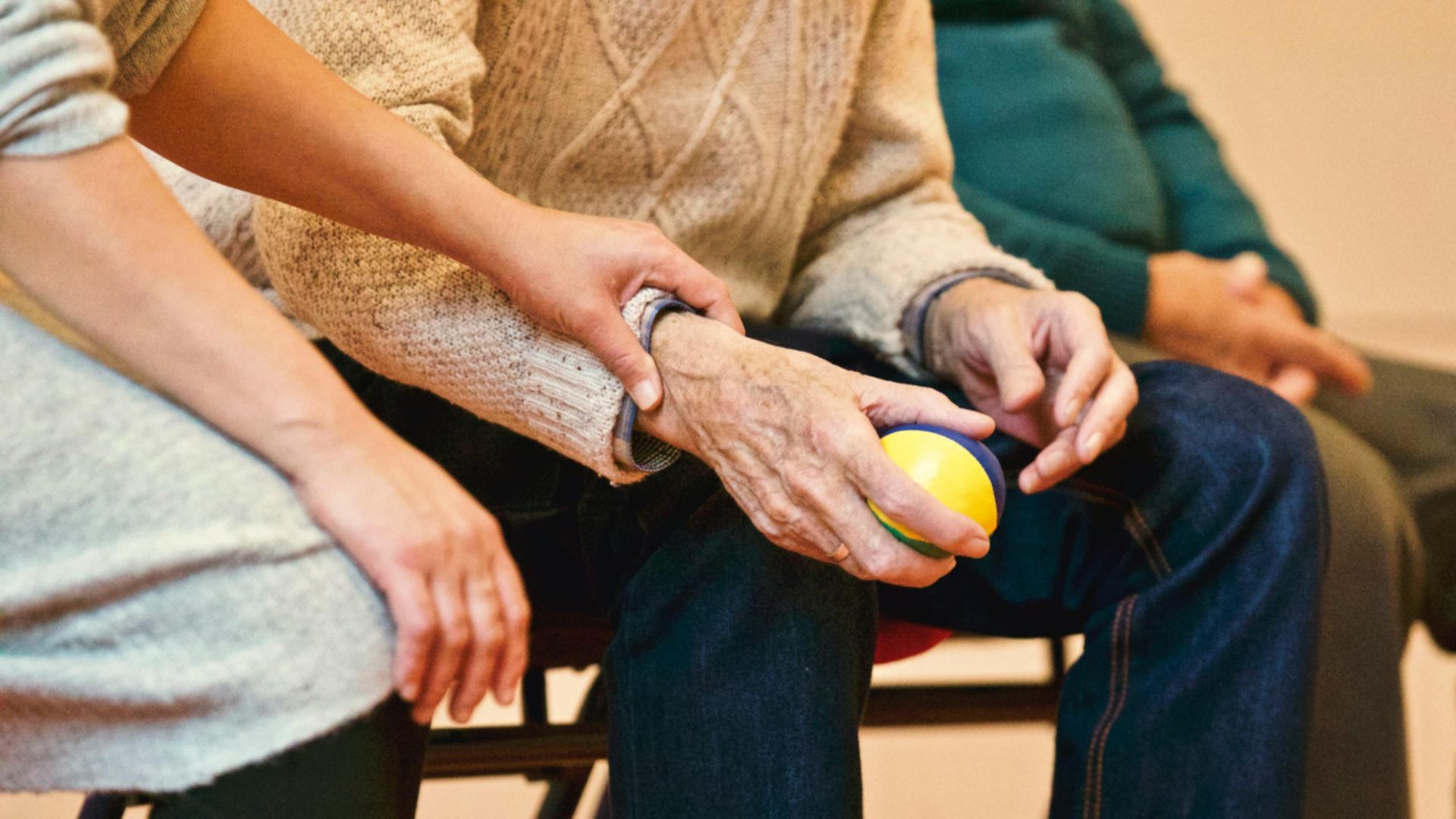 A carer's hand resting gently on an elderly client's hand